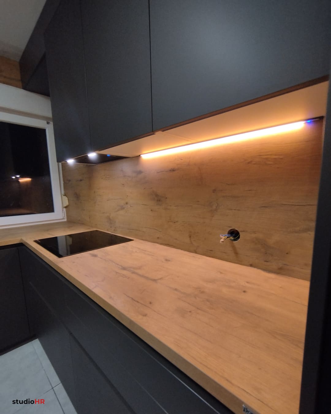 LED rasvjeta ispod gornjih elemenata u DanKuchen Silbermond kuhinji s drvenim backsplashom
